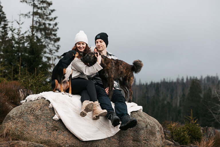 Inniges Kuscheln von Mann und Frau mit ihren beiden Tierschutzhunden am Oderteich im Harz - ein herzliches Familienbild voller Liebe und Verbundenheit inmitten der Natur.